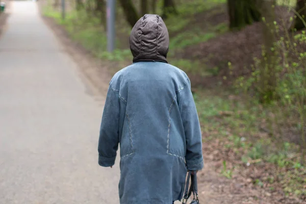 女性が公園を歩いている 通りに一人でいる年配の女性 男が歩いている 後ろから女性を撃つ — ストック写真