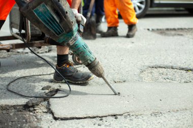 Asfaltı bir kaya matkabıyla kaldırıyor. Yoldaki asfalt tabakasını kaldırıyorum. İşçi bir kaya matkabı tutuyor. Yol tamiri. Elektrikli çekiç kullanarak..