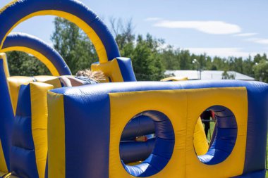 Şişirilebilir engelli koşu parkuru. Parktaki şişme bina. Çocukların mutluluğu için bir yer. Oyun parkı. Ama sarı-mavi.