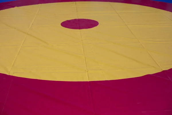 A sports ground for wrestling. Soft flooring for sport. Ring for judo and karate. The background is from the red circle in yellow. Soft coverage for workouts and tournaments.