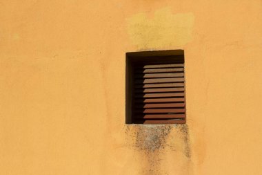 Binanın dışındaki havalandırma penceresi. Kanal örgüsü. Sıcak havanın havalandırmadan çıkarılması. Sarı duvar ve kahverengi ızgara.