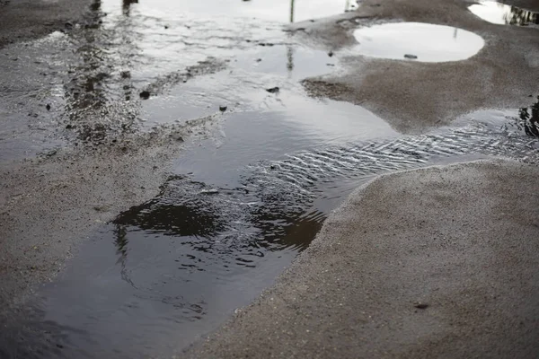 Dirty puddle on the road. Drain the water on the roadway. Flooding of the road after the rain.