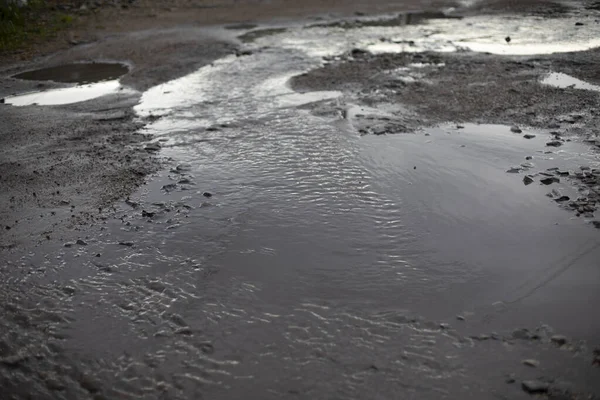 Dirty puddle on the road. Drain the water on the roadway. Flooding of the road after the rain.