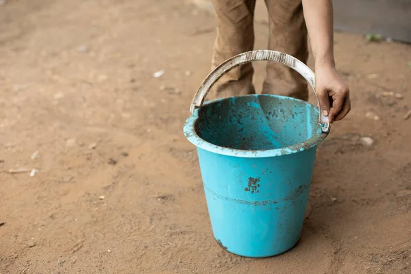 那孩子手里拿着一个桶 蓝色的桶在手 那男孩玩水桶和铲子 一个孩子在院子里玩耍时把衣服弄脏了 — 图库照片