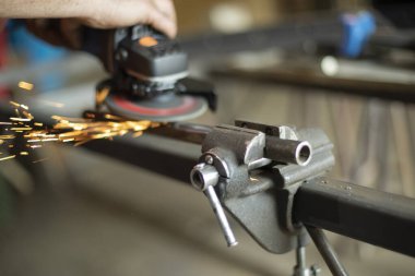 Metal öğütme. Elektrikli aletlerle çelik işleme. Bir adam garajda bir parça üzerinde çalışıyor. Metal atölyesi. Dönen disk.