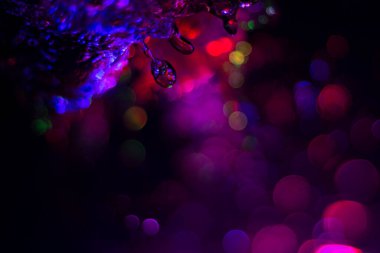 Renkli su dokusu. Farklı renklerde yanan su damlaları. Çeşmeden yakın plan su çekimi. Parlak renkler su akış arkaplanı.