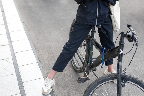 这个女孩骑自行车站着 街上的那个少年把她的脚踩在了踏板上 这个女学生在城里打滚休息 — 图库照片