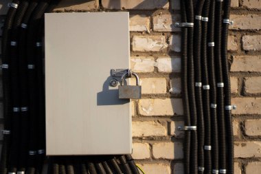 Electrical panel on the street. Lock on the electrical switch. Drawer on the wall. Voltage monitoring equipment.