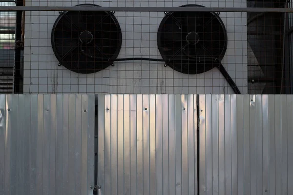 Steel fence and cooling devices in the warehouse. The production part of the office building. A view of the yard here at the store. A stainless steel fence.