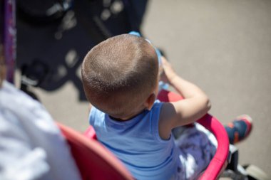 Bebek arabasında küçük bir çocuk. Çocukla birlikte güneşte yürü. Bebek için sıcak bir gün. Bebeğin kafası..