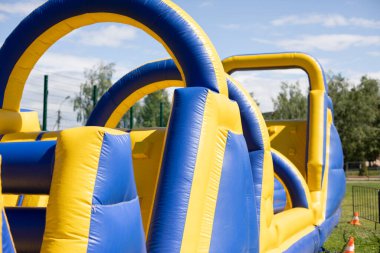 Şişirilebilir engelli koşu parkuru. Parktaki şişme bina. Çocukların mutluluğu için bir yer. Oyun parkı. Ama sarı-mavi.