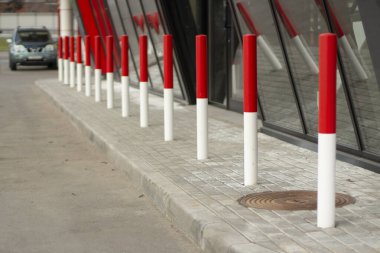 Otoparktaki kırmızı direkler. Araba trafik sınırlayıcıları. Yol boyunca kırmızı-beyaz sütunlar. Önleyici sınırlama.