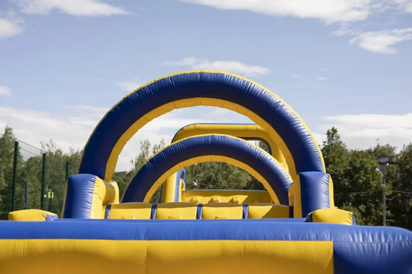 楽しいためのインフレータブル障害物コース 公園内のインフレータブル構造 子供たちの喜びのための場所 遊び場 黄色の青です — ストック写真