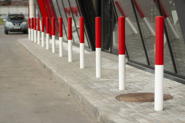 Red posts in the parking lot. Car traffic limiters. Red-white pillars along the road. Preventive limitation.