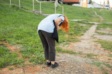 Kız yerdeki bir şeye bakmak için eğildi. Kız küçük bir şey düşürdü. Kadın giysilerinde pislik arıyor..
