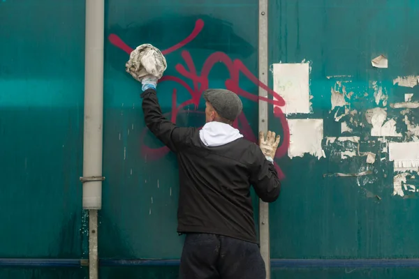 İşçi yazıtlardan duvarı temizler. Vandal grafiti temizliği. Yaya geçidini boyadan yıkıyorum. Sprey boyayla boyama.