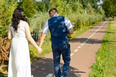 Yeni evliler parkın patikasında el ele yürüyorlar. Bir erkek ve bir kız romantik bir yürüyüş yapıyorlar. Aşıklar yazın parkta yürür..