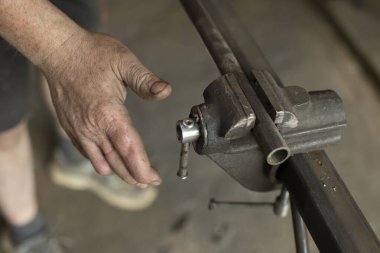 Adam ahlaksızlıktaki rolü düzeltiyor. El ve metal. Çelikten bir parçanın üretimi. Garajda çalışıyorum..