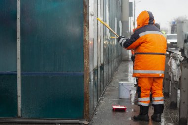 Ressam beyaz boyayla resim yapar. Boyayla grafiti yapıyor. Duvarı boyuyorum. Bir işçi, vandalist bir yazının üstünü boyuyor..