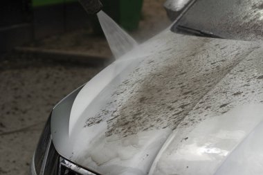 Araba yıkama. Araba bir su püskürtüsünün basıncıyla yıkanır. Arabanın yüzeyindeki kiri temizlemek için su spreyi kullanmışlar..