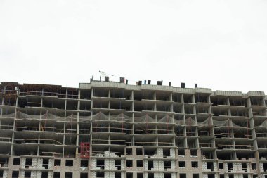 Şehirde inşaat halindeki bir ev. Bir sürü beton zemin. Binanın ön cephesine bakma işlemi devam ediyor..