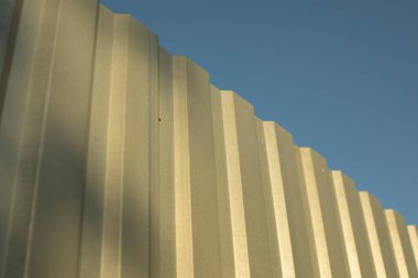 Boyanmamış metalden yapılmış basit bir çit. Paslanmaz çelik çit parçaları. Galvanize materyalin endüstriyel tasarımı.