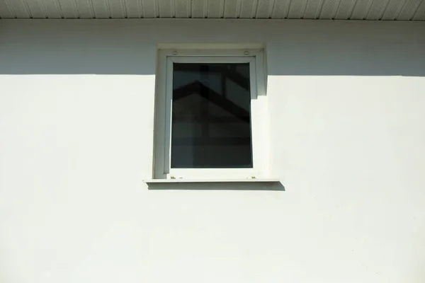 白い壁の白い窓 明るい日差しの中でプラスチック製の小さな窓 建物の外観 白い壁のファサード — ストック写真