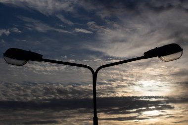 Şehir lambası gökyüzüne karşı. Akşam bulutlarının arka planına karşı ışıkları söndürdü. Şehir manzarası ayrıntılarda gizlidir..