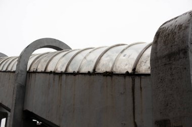Otobandan geçen yayalar. Yolun karşısındaki tünel. Üzerinde yayaların yürüdüğü borunun çatısı. Kemerli plastik yüzey somut temellere dayanır.