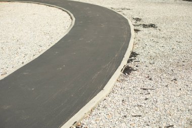 Parkta yeni asfalt yol. Bisikletçiler için dar park yolu. Onarılmış yol yüzeyi.