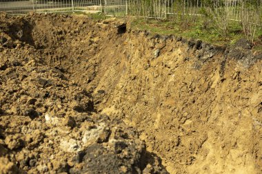Toprağa borular döşüyorlar. İnşaat sırasında kazılmış toprak. Ağır makinelerin çalışmasının sonucu. Arazi, yeraltı tesislerinin kurulması için hazırlandı..