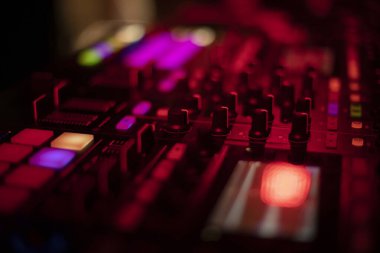 Karanlıkta müzik mikseri. Uzaktan kumandanın düğmeleri yanıyor. Ses çalar neon parıltısı. Müzik çalmak için DJ konsolu.