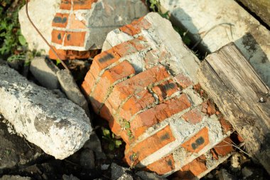 Duvarın kırık parçaları. Harabe bir ev. Tuğladan yapılmış parçalar. İnşaat atığı çöplüğü. Kırmızı tuğla kırıldı ve sokakta yatıyor..