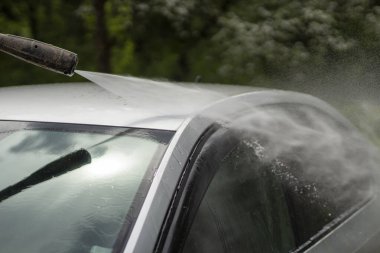 Araba yıkama. Araba bir su püskürtüsünün basıncıyla yıkanır. Arabanın yüzeyindeki kiri temizlemek için su spreyi kullanmışlar..