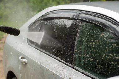 Araba yıkama. Araba bir su püskürtüsünün basıncıyla yıkanır. Arabanın yüzeyindeki kiri temizlemek için su spreyi kullanmışlar..