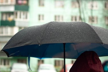 Yağmurdan şemsiyesi olan bir adam. Dışarıda hava yağmurlu. Şemsiye bir adamın ellerinde..