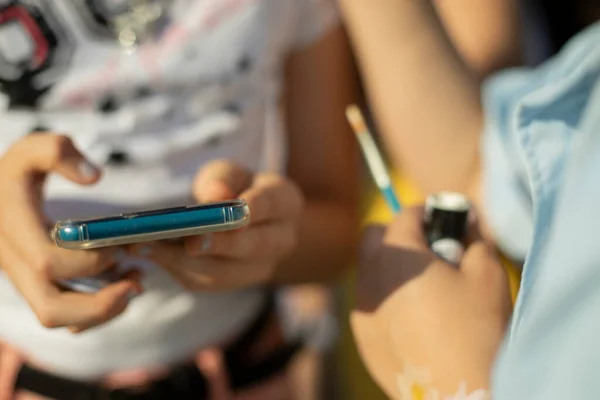 Smartphone in the hands of a child. Use of the phone by a schoolboy. Children and the Internet. The child uses a smartphone in the summer.