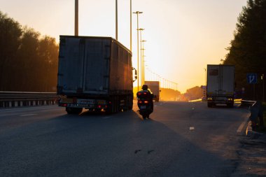 Otoyolda gün batımı. Güneş otoyolun üzerinde batıyor. Yüklü otoyol. Arabalar akşamları şehirden yola çıkar..