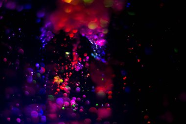 Renkli su dokusu. Farklı renklerde yanan su damlaları. Çeşmeden yakın plan su çekimi. Parlak renkler su akış arkaplanı.