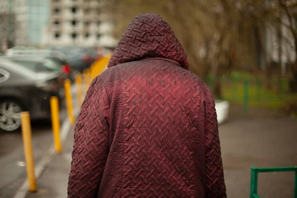 雨の中の女性が通りを歩いている 悪天候で頭の上にフード ロシアの女性は仕事から帰ってくる — ストック写真