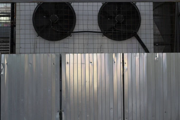 Steel fence and cooling devices in the warehouse. The production part of the office building. A view of the yard here at the store. A stainless steel fence.