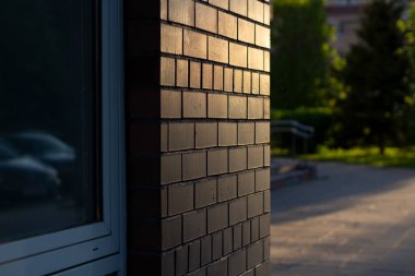 Binanın duvarında güneş ışığı var. Batan güneş tuğla duvarı aydınlatıyor. Kentsel gelişimin ayrıntıları.