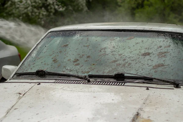 汚れた車が洗われている 白い車の泥で覆われた 車は水の下の街にある — ストック写真