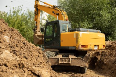 İnşaat makineleri çukur kazıyor. Kazıcı toprağı kepçeler. Boru döşeme. Büyük çalışan kazıcı.