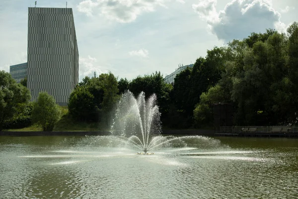 Fountain on the water. Jets of water in the lake. City park with a pond. Splashes from jet pressure.