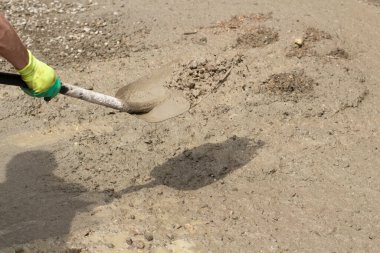 Kumlu kürek. Kürekle kum fırlatıyor. İnşaat alanında çalışıyorum. Yoldaki toprağı temizliyorum..