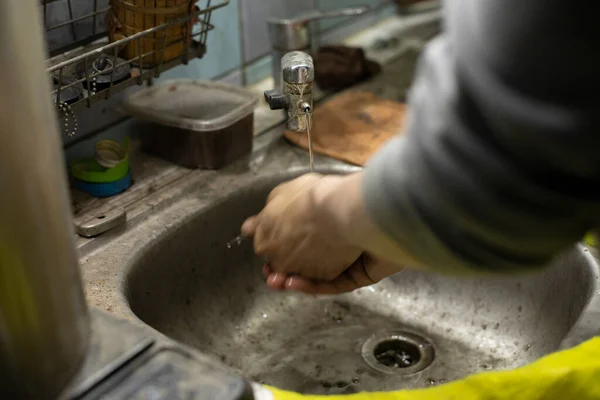 Hand washing in the sink. The bachelor washes his fingers with soap. Dirty sink in the house. Water pours from the tap.