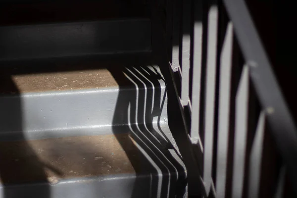 Stairs inside the house. Steps made of concrete. Details of the architect of the building. Gray steps and the shadow of the railing.