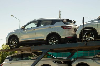 Yeni arabaların kamyonla taşınması. Forkliftte bir sürü yeni makine var. Yabancı arabalar römorkta tamir edildi..