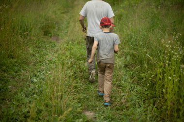 Çocuk babasıyla birlikte tarlayı geçiyor. Bitkilerin arasındaki adam. Yetişkin bir adamla okul çocuğu böğürtlen aramaya gider..
